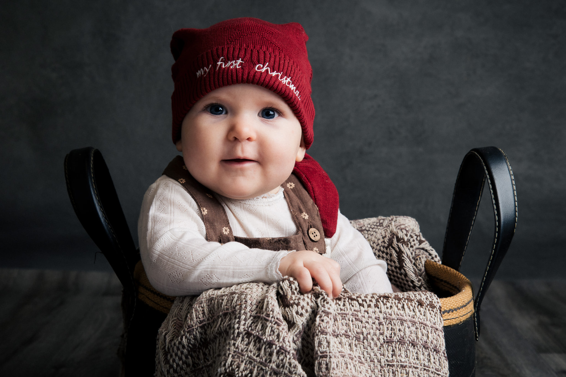 Baby i rød nissehue med teksten my first christmas siddende i kurv i studie i Aabybro