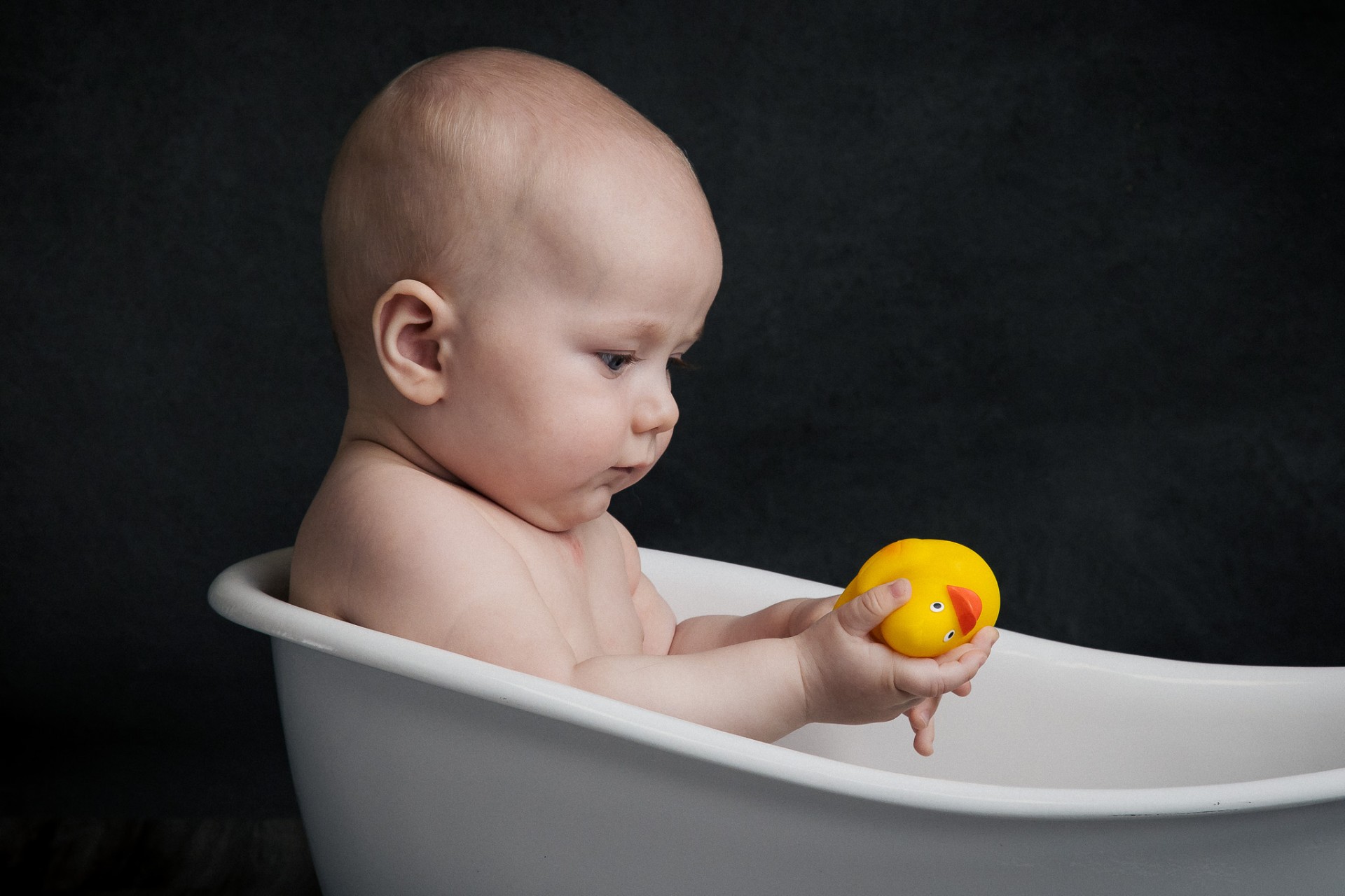 Baby i badekar med badelegetøj under kreativ studiefotografering