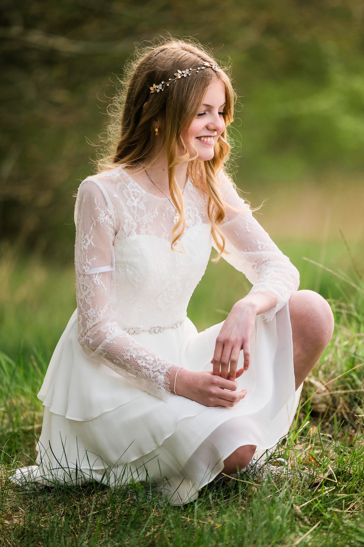 Konfirmand i hvid kjole på græsmark