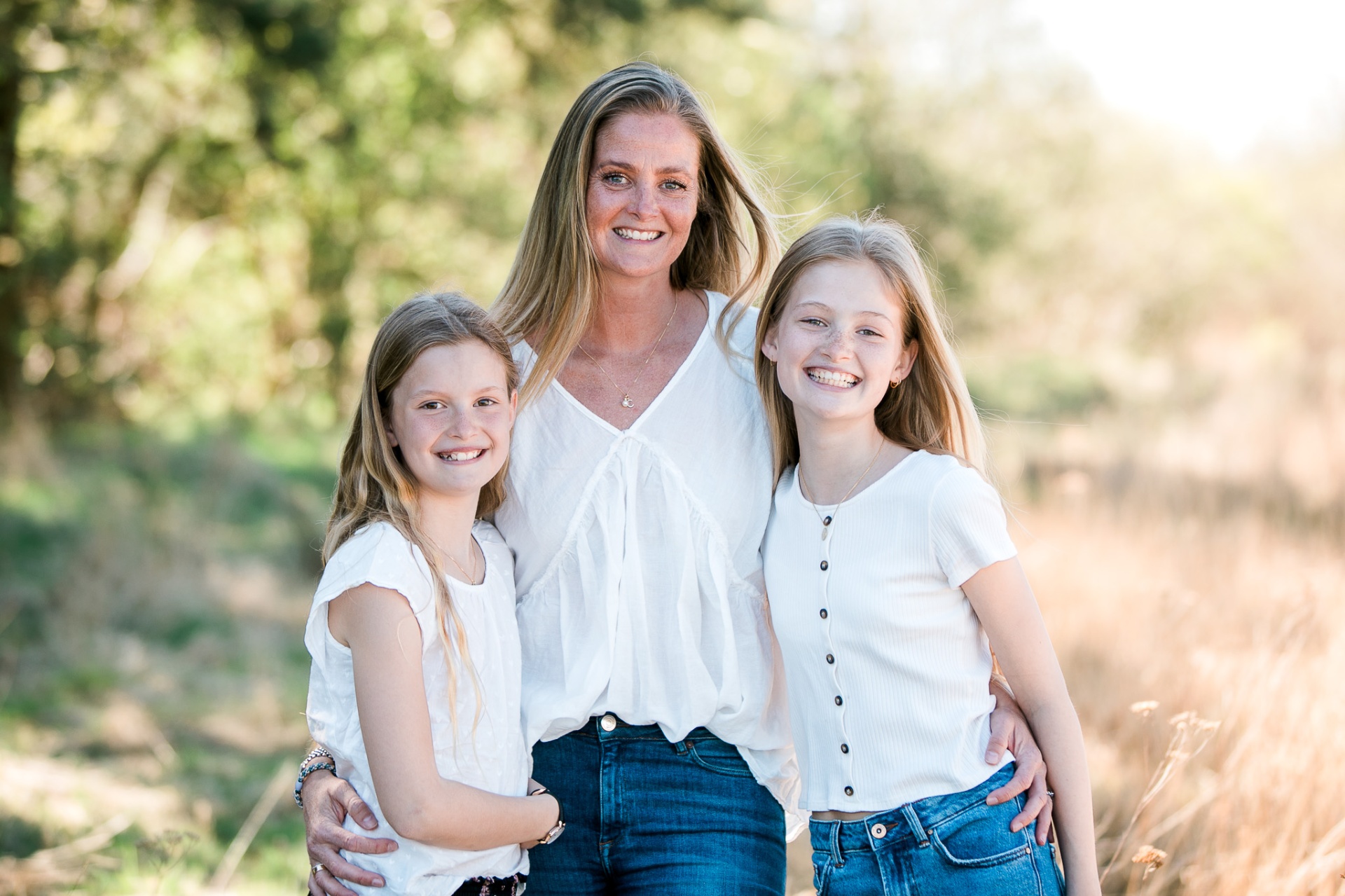 Mor med to smilende døtre i naturskønne omgivelser ved Nørresundby