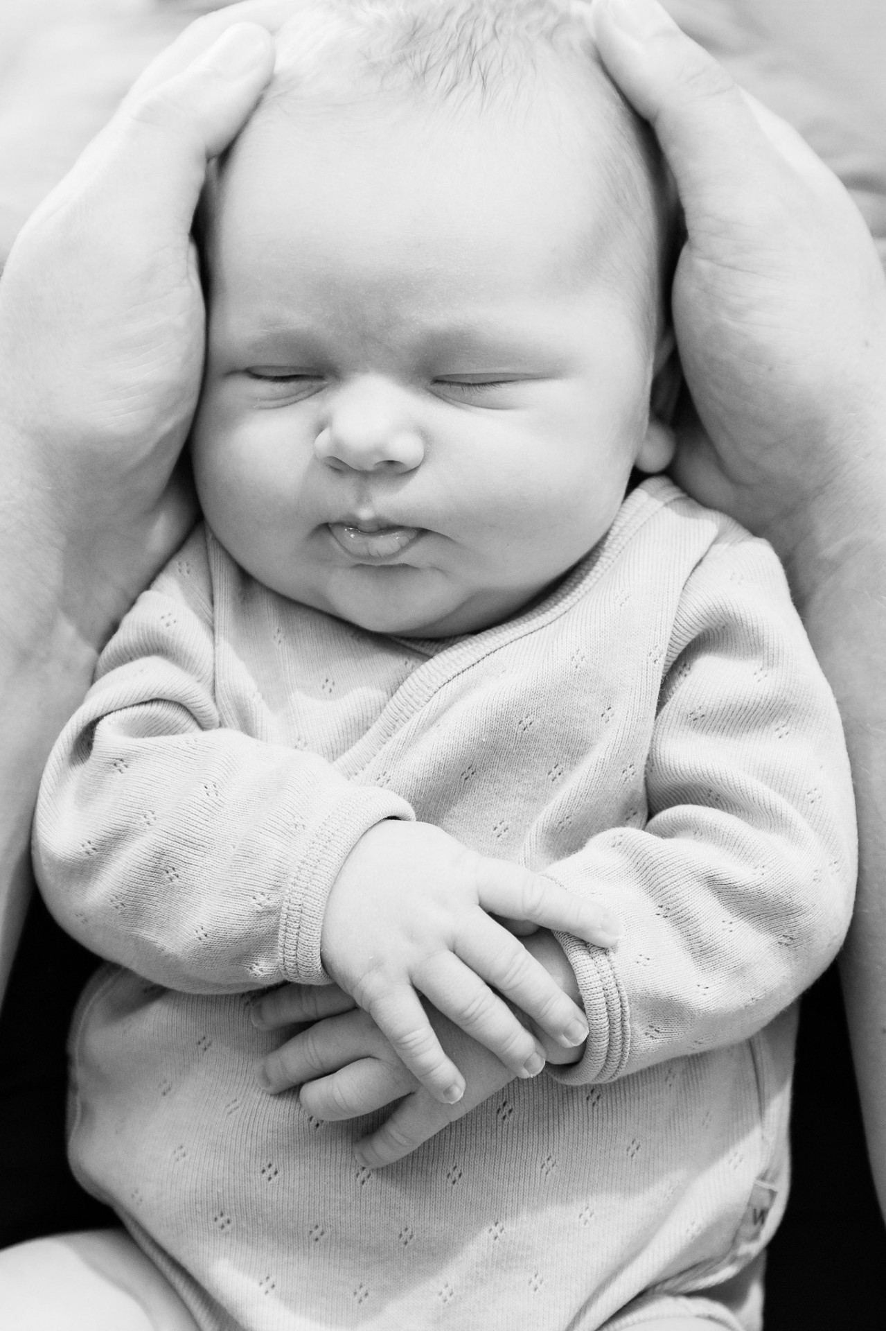 Sovende nyfødt i fars hænder – sort/hvid babyfotografering Aalborg
