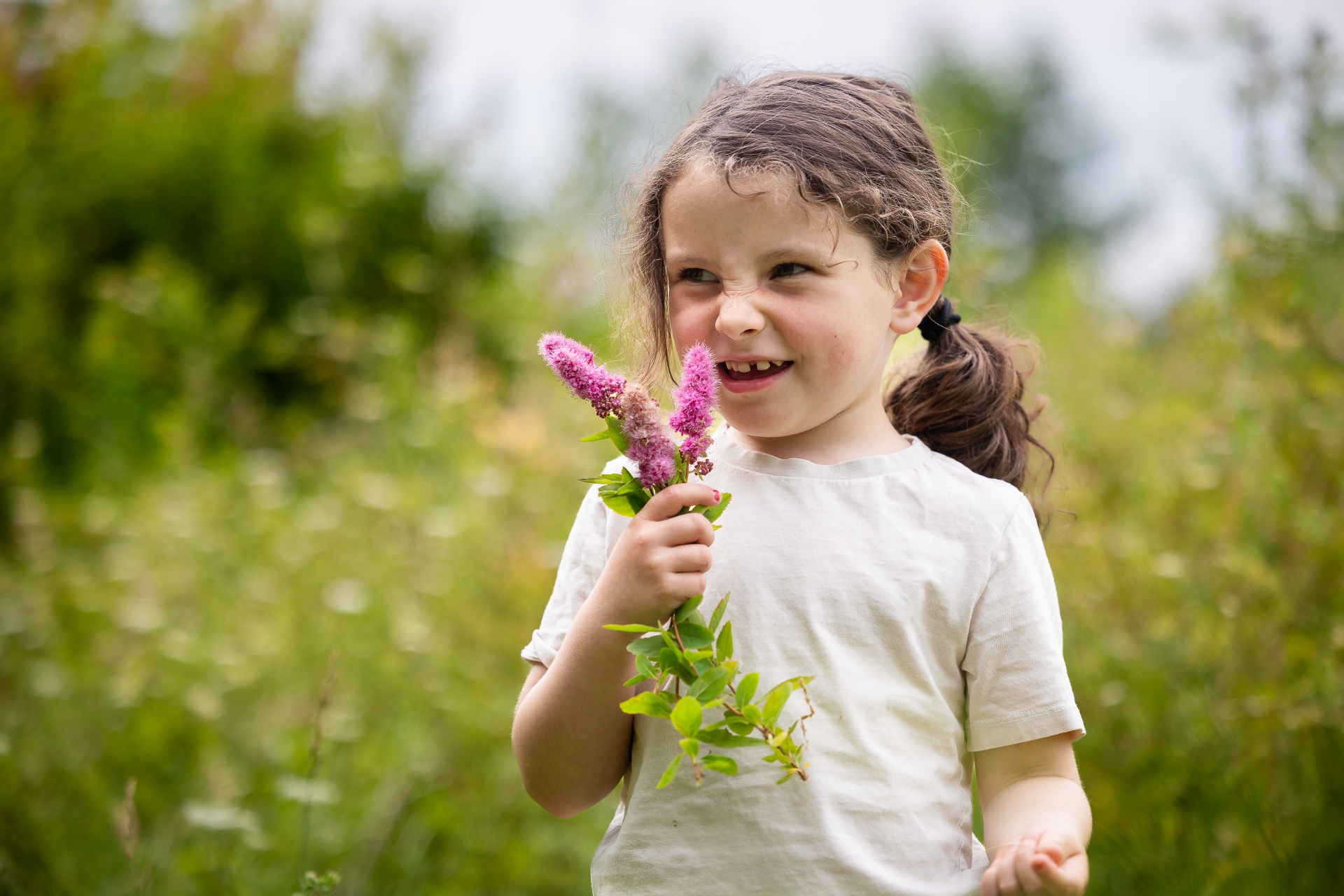 Pige med blomster i hånden smiler i sommerlys ved Brønderslev