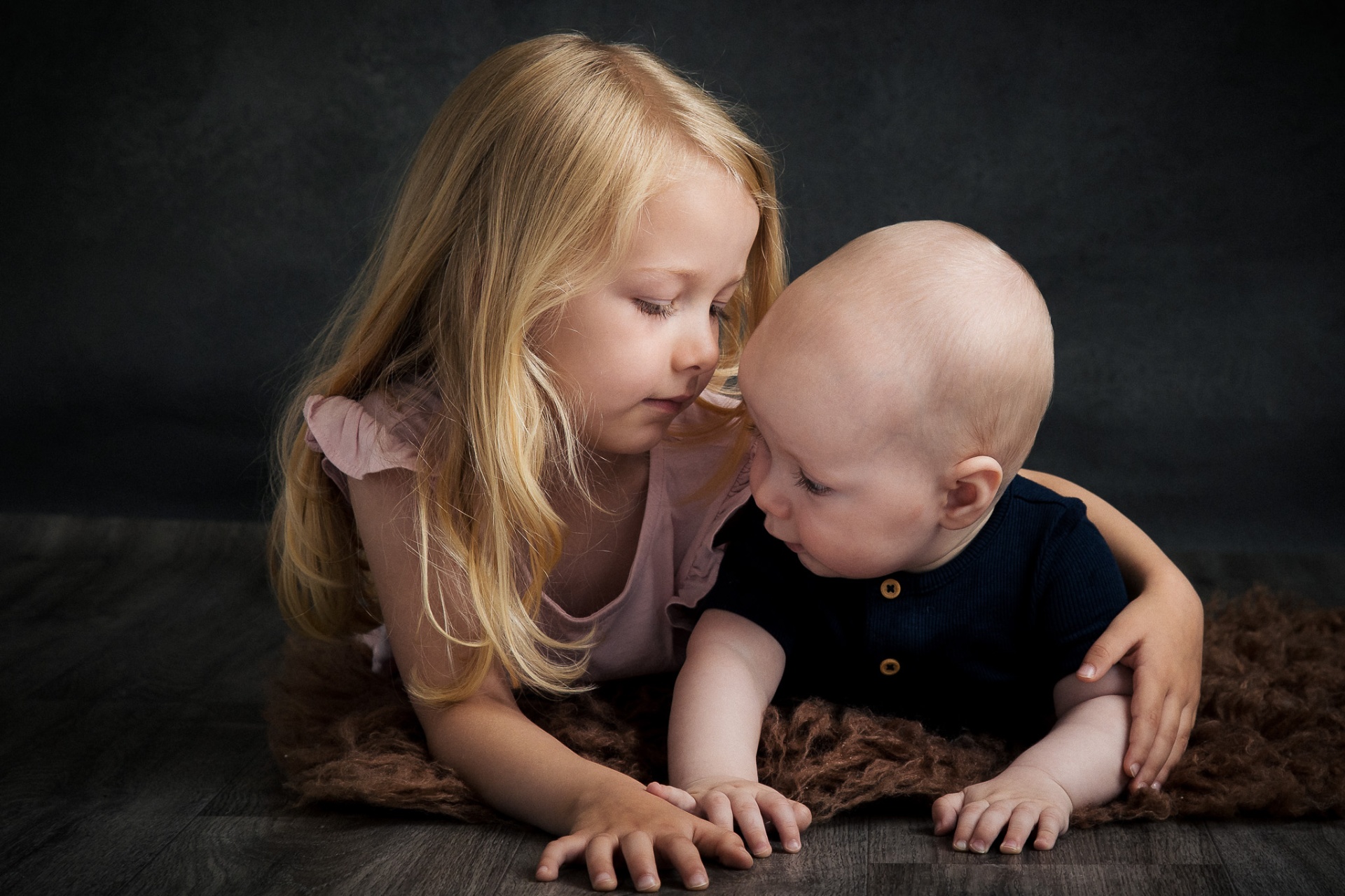 Storesøster krammer kærligt sin baby-bror i intim studieoptagelse