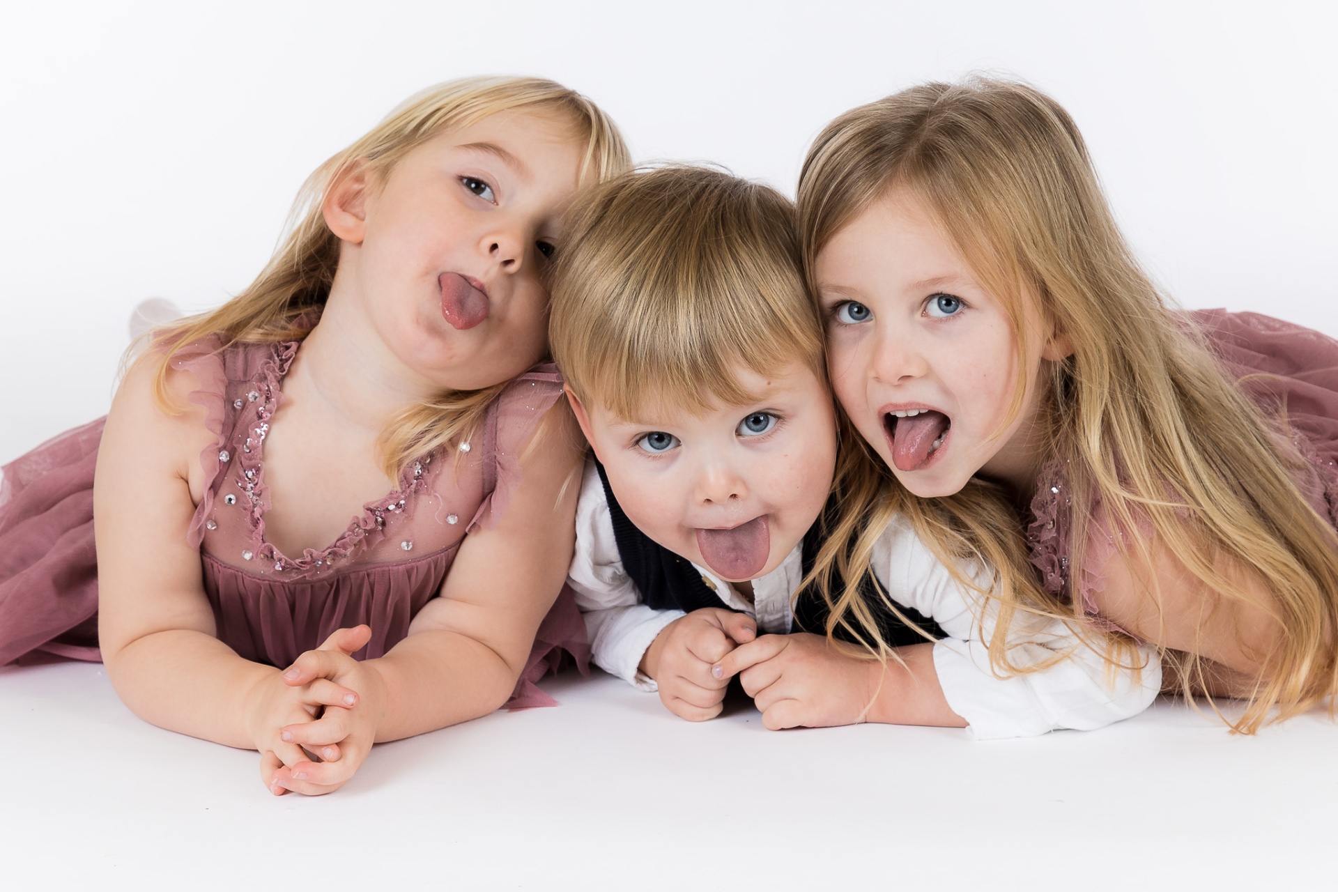 Tre søskende laver sjove ansigter og rækker tunge under fotografering