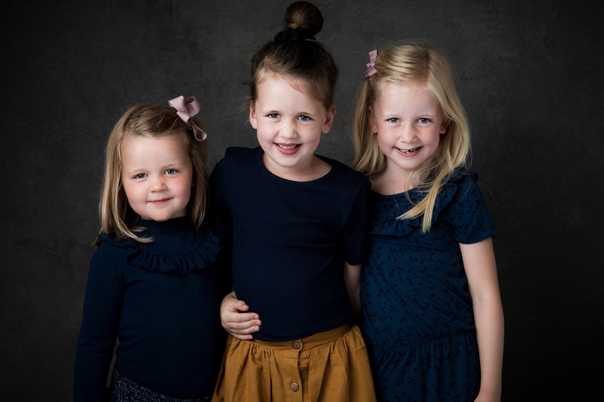 Tre søstre i matchende blåt tøj fotograferet i studie